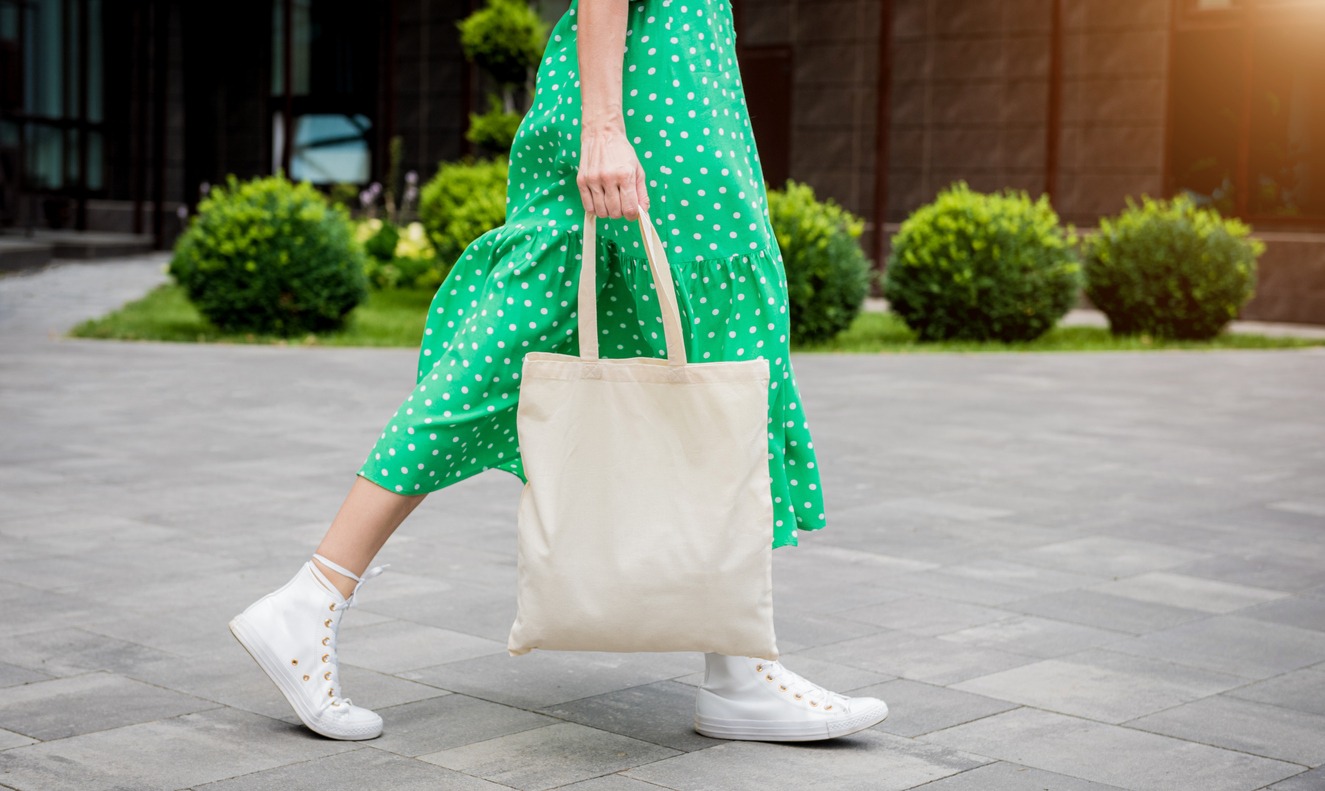 Young beautyful woman with linen eco bag on city background